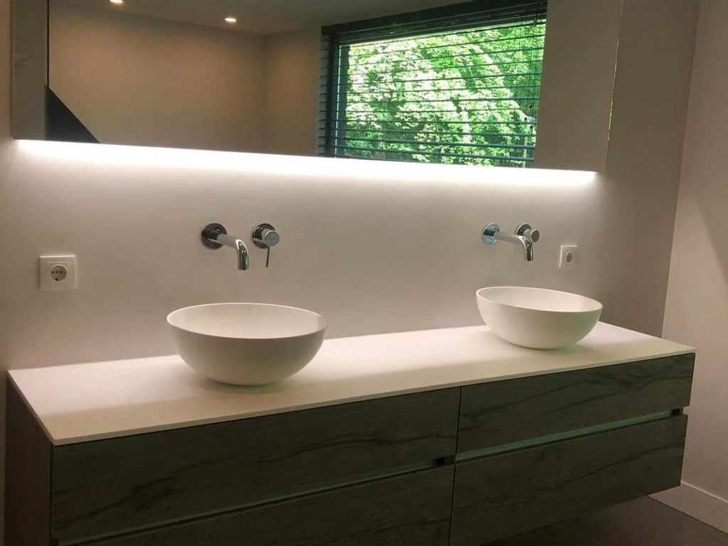 Smooth plastered bathroom wall with a double vanity and backlit mirror, finished by Stuc Design Apeldoorn