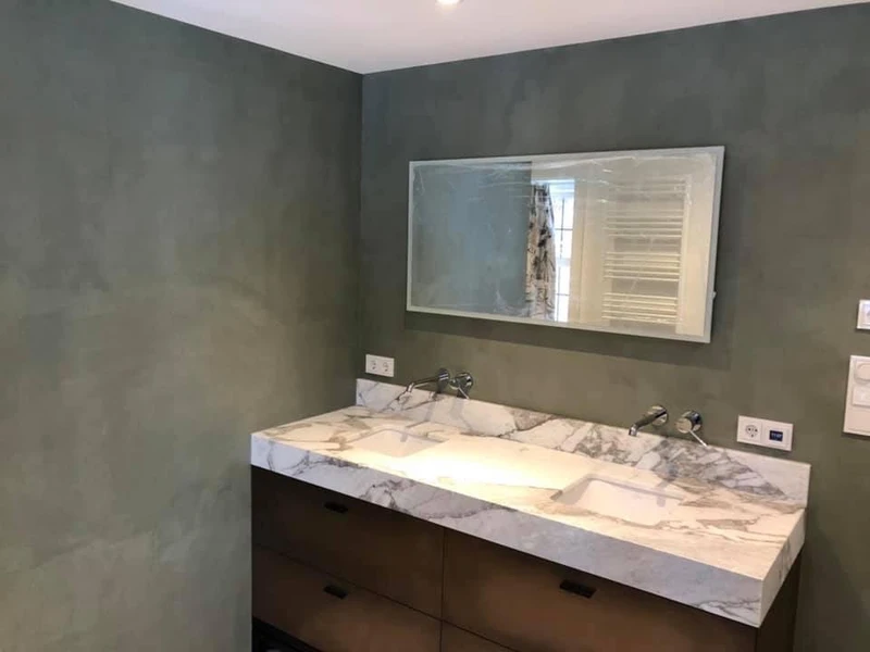 Badkamerwand in beton ciré met brede spiegel en marmeren wastafel